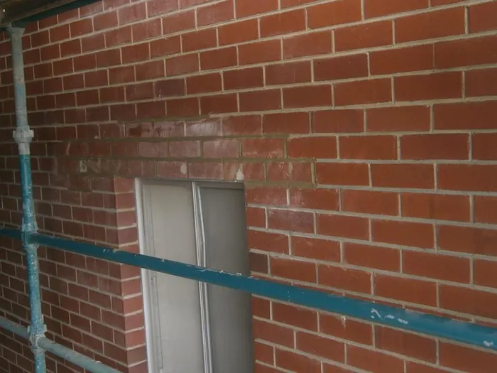 Cracked brickwork beside a window, before repair